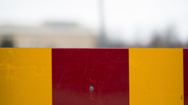 Detalj av ett avspärrningsstaket i gula och röda varningsfärger.